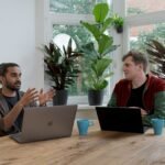 man in red and black crew neck t-shirt using silver macbook